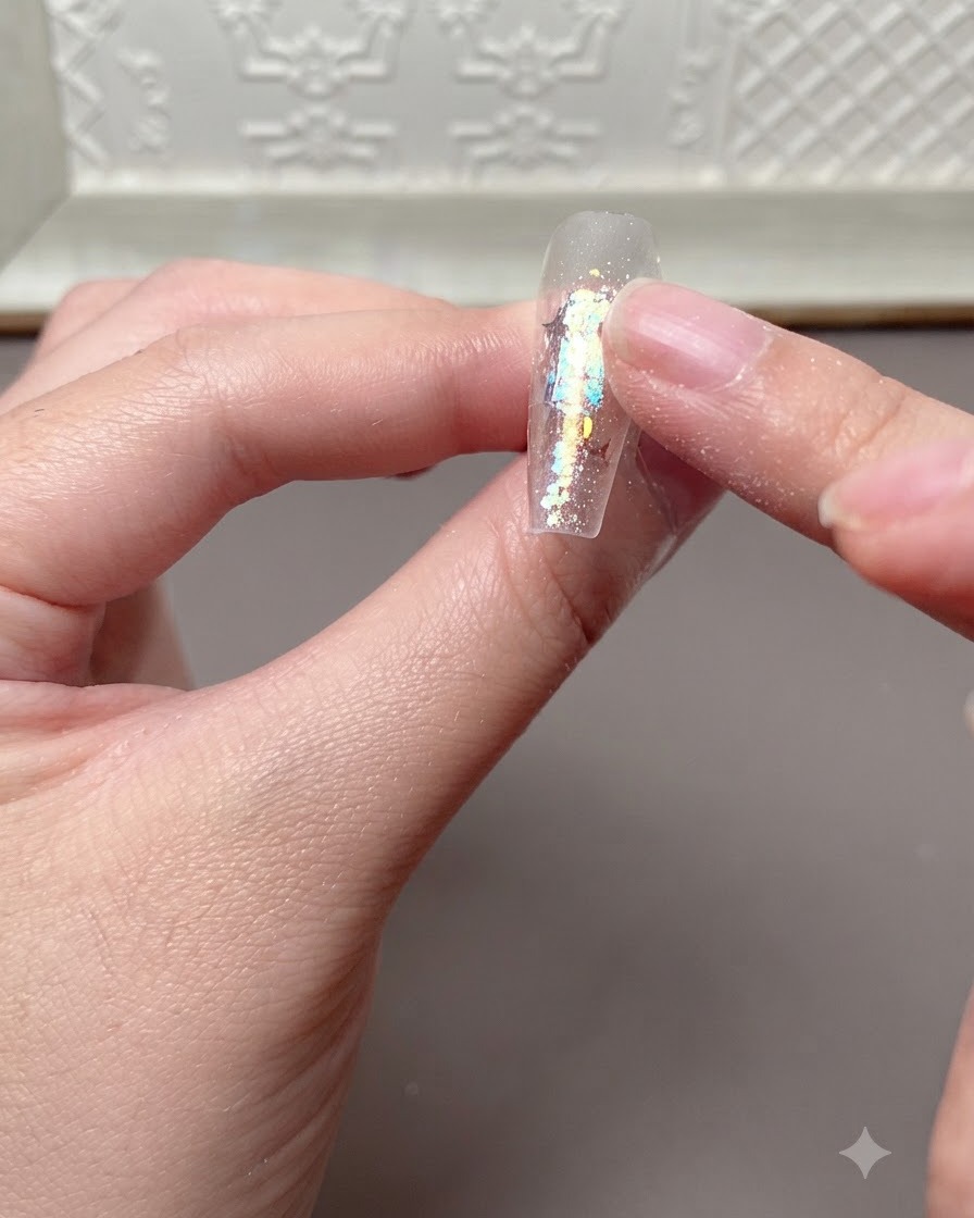 UV 또는 LED 램프에서 큐어링된 네일 연장 팁 표면을 손가락으로 가볍게 눌러 확인하는 모습.