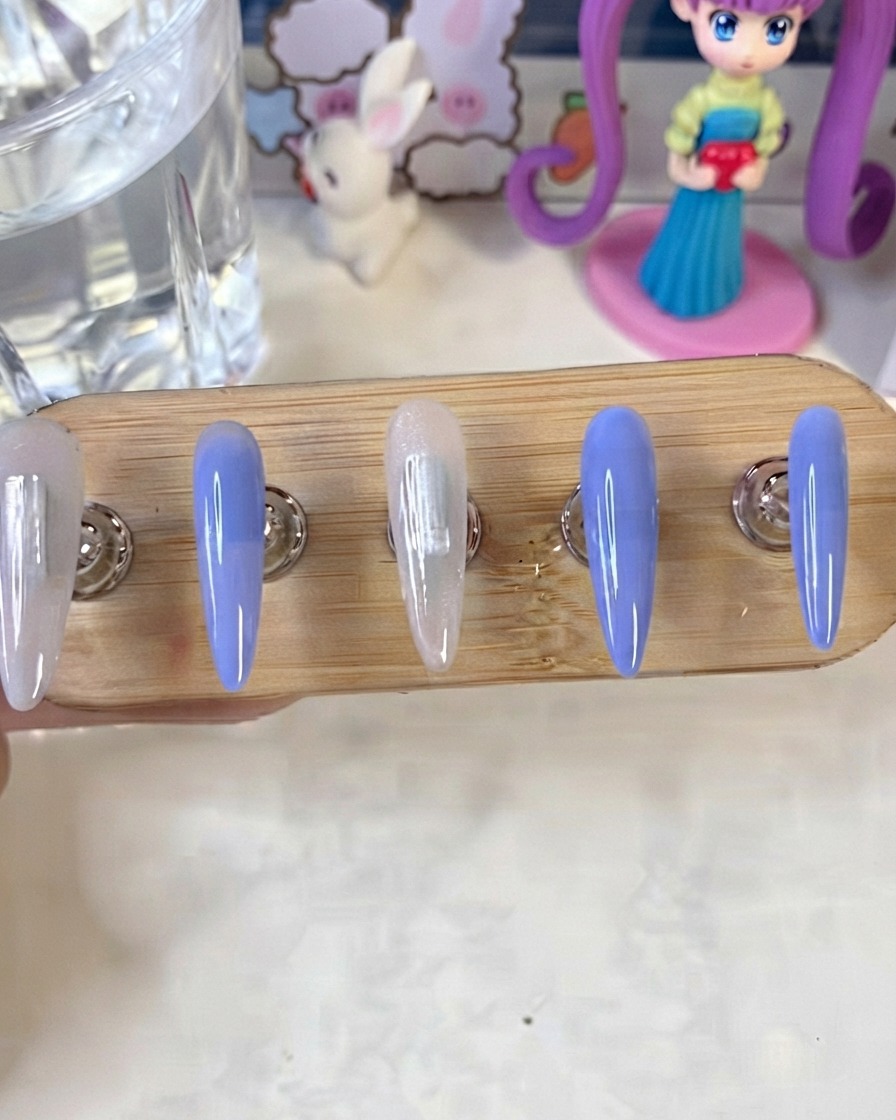 UV/LED 램프 아래에서 큐어링 중인 블루 및 밀키 화이트 컬러 네일이 있는 네일 스탠드.