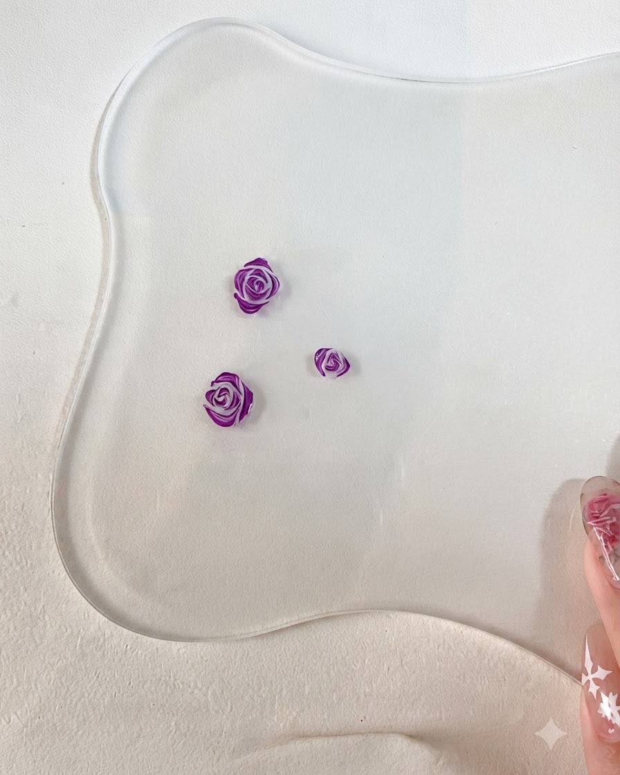 조각된 3D 장미 꽃잎의 가장자리에 짙은 보라색으로 디테일한 윤곽선을 추가하는 세필붓의 클로즈업.