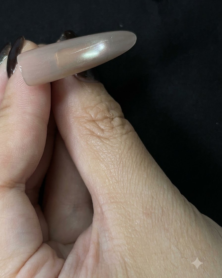 어두운 배경을 바탕으로 부드러운 반사 중심선이 보이는 완성된 롱 누드 자석 네일 팁.