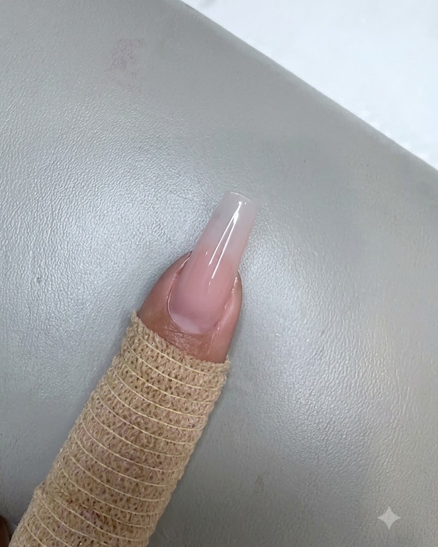 보랏빛 미니 UV LED 램프 아래에서 누드 핑크 젤이 매끄럽게 발려 큐어링되고 있는 손톱.