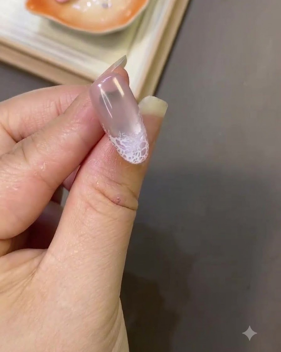 끝부분의 부드러운 표면 질감을 가진 완성된 화이트 레이스 디자인과 손톱 끝의 클로즈업 샷.
