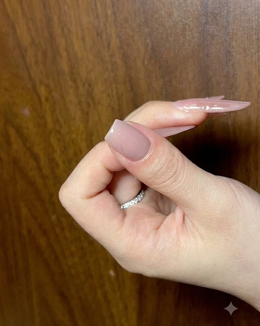 매끄러움을 확인하기 위해 각도를 주어 바라본, 완성된 누드 베이스 레이어가 있는 손톱을 들고 있는 손.