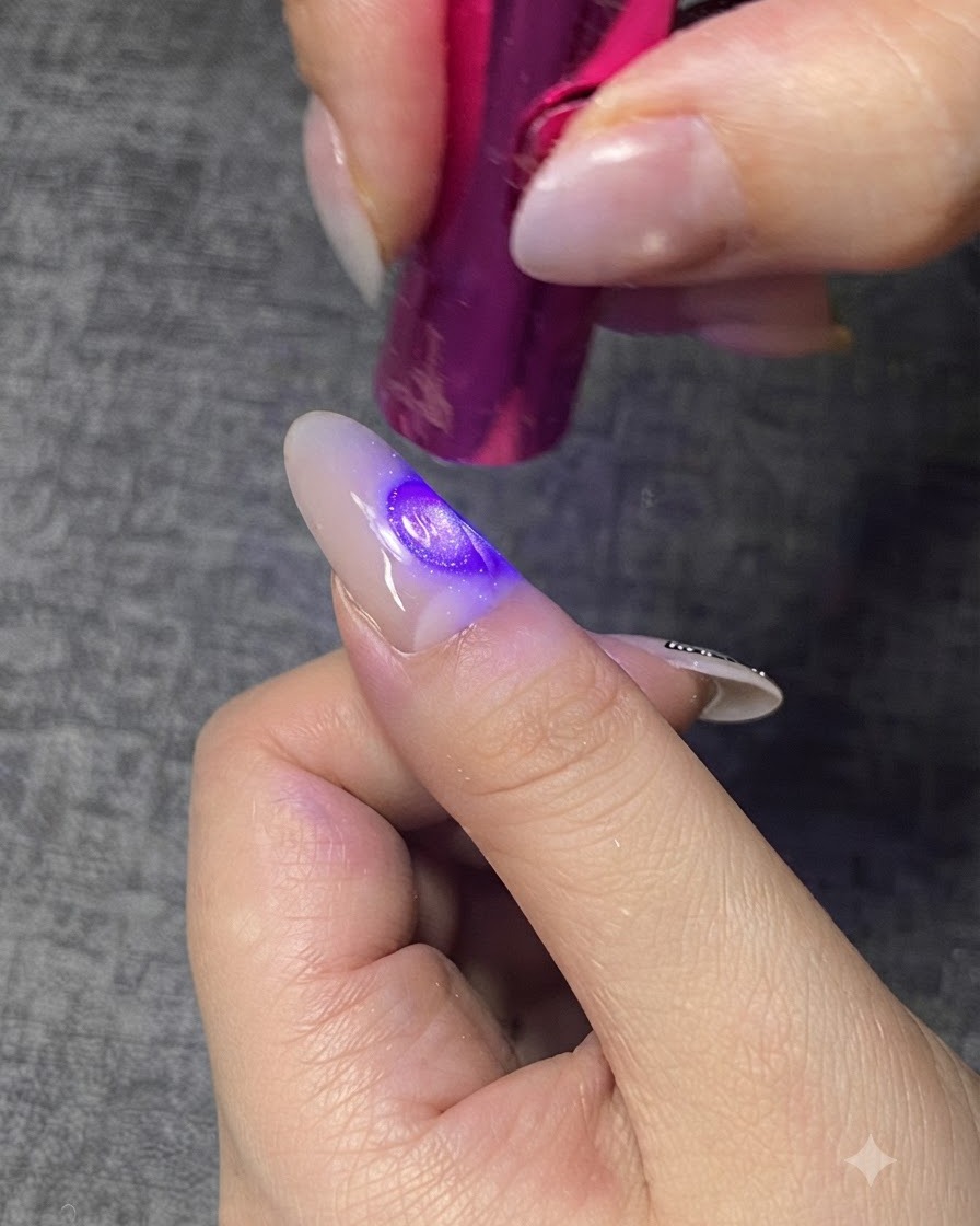 미니 퍼플 UV/LED 램프로 손톱의 클리어 젤 층을 큐어링하는 모습.