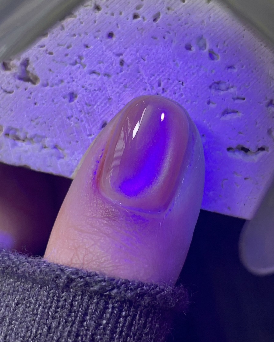 보라색 UV/LED 미니 램프 아래에서 손톱이 경화되는 모습.