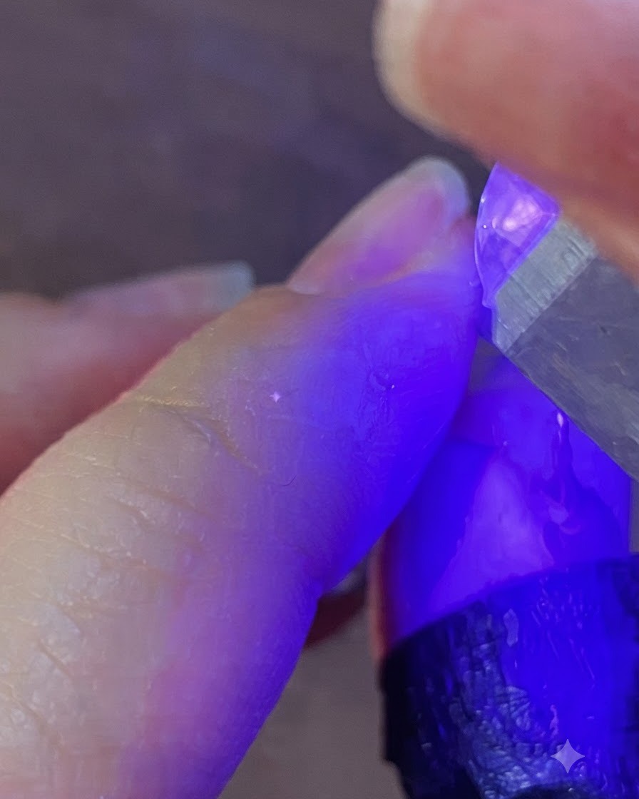 휴대용 UV LED 네일 램프가 보라색 빛을 발하며 손톱을 큐어링하는 모습.