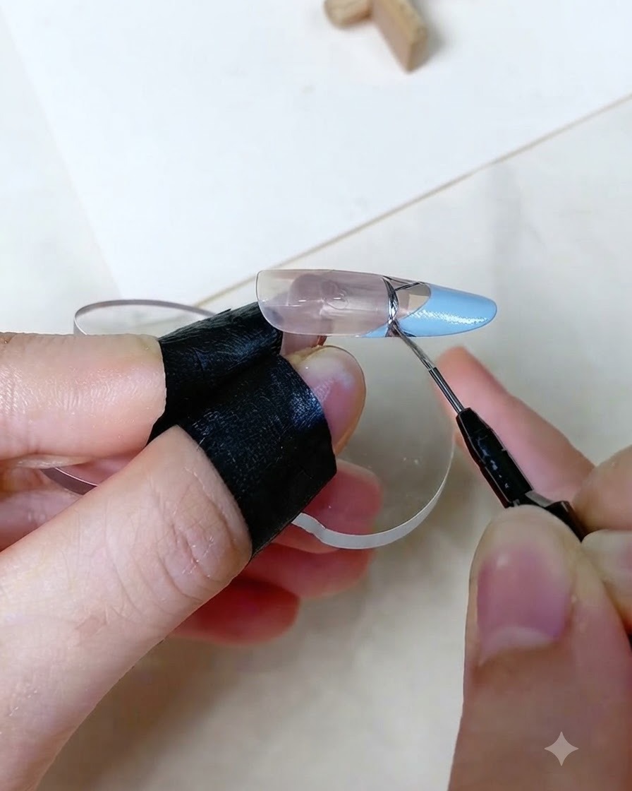 베이비 블루 프렌치 팁 경계선에 정교한 메탈릭 실버 라인을 그리는 세밀한 브러시 작업 클로즈업.