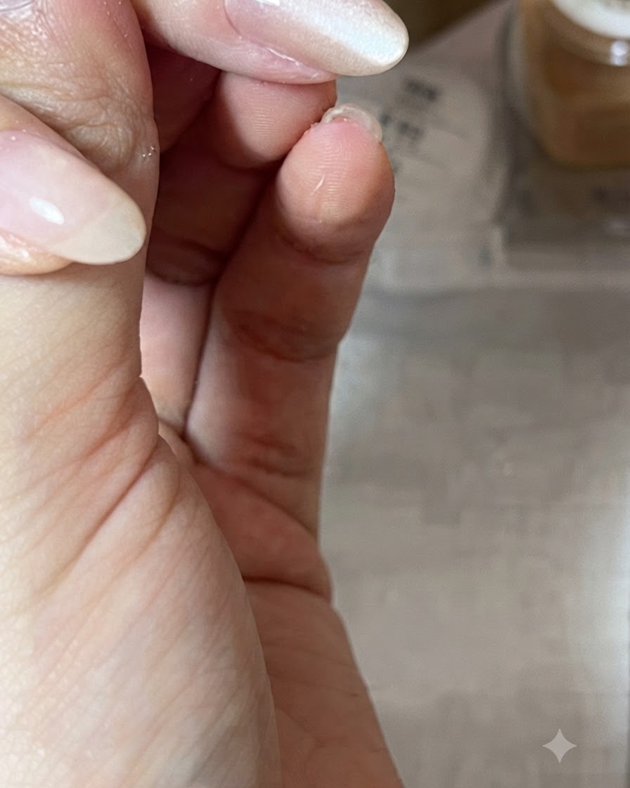 윤기 나는 누드 톤 젤이 발린 네일 위로 원통형 자석을 대각선으로 들고 캣츠아이 빛 반사를 디자인하는 클로즈업.