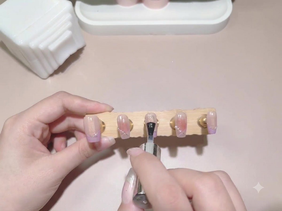 완성된 칠해진 가짜 네일 디스플레이 스탠드 전체에 탑 코트 브러시가 적용되는 모습.
