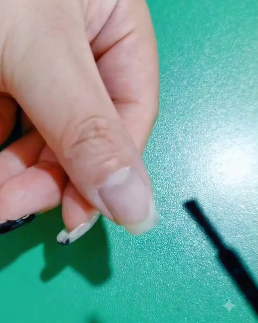네일 브러시로 자연 손톱 위에 첫 번째 블랙 젤 폴리시를 바르는 모습.