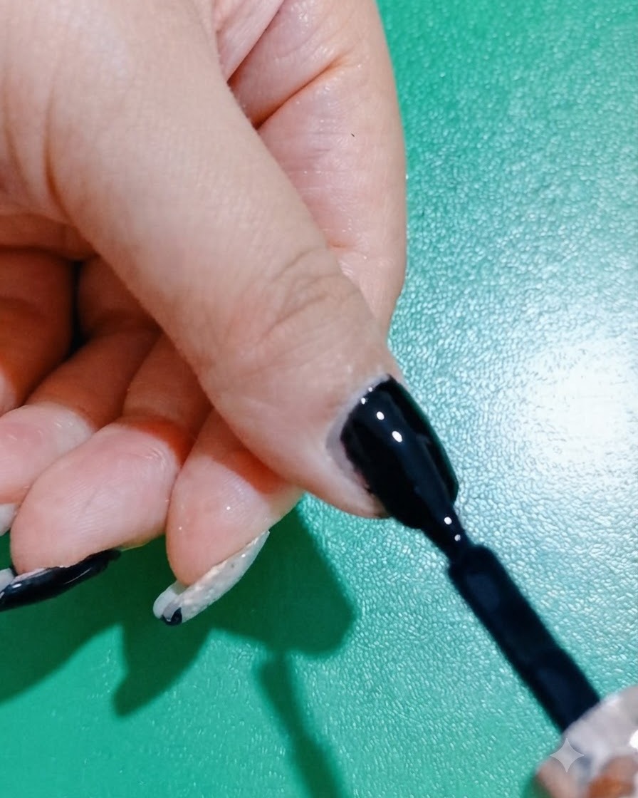 손톱 위의 블랙 젤 폴리시 레이어를 브러시로 매끄럽게 정리하고 다듬는 모습.