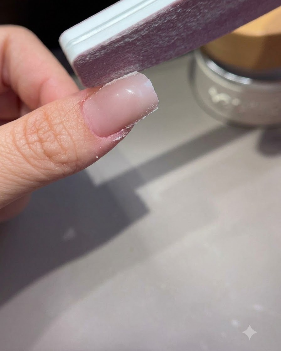 핸드 파일로 연장된 아크릴 또는 젤 네일의 사이드월을 모양 잡고 다듬는 모습.