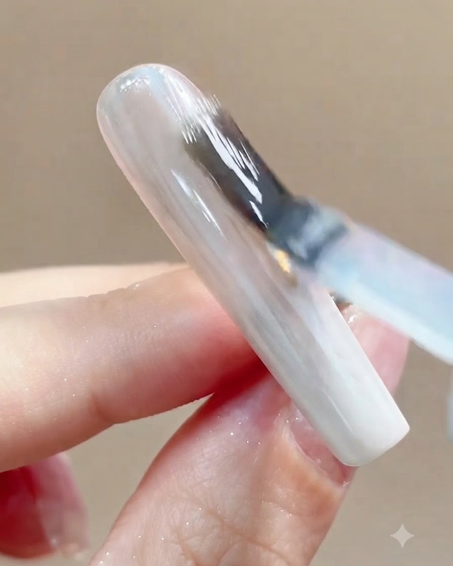 탑코트 도포 후 UV 또는 LED 큐어링 램프 아래에 네일이 놓여 있는 클로즈업 뷰.