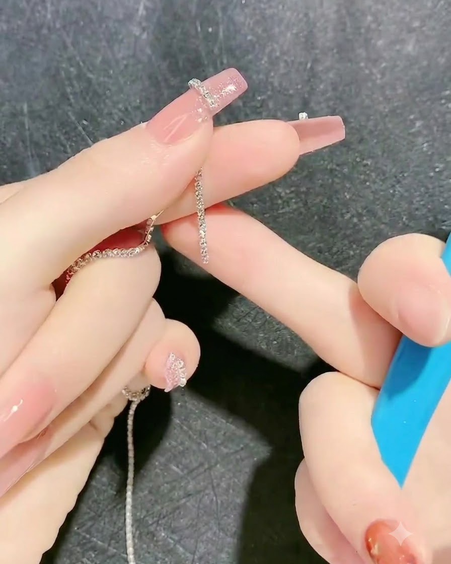 왁스 피커나 핀셋으로 끈적한 젤 아웃라인 위에 스톤 체인 스트립을 올리는 모습.