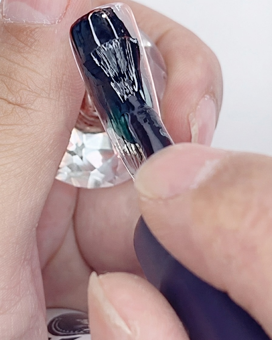 인공 네일 팁에 블랙 젤 폴리시 첫 번째 코트를 바르고 있는 브러시.