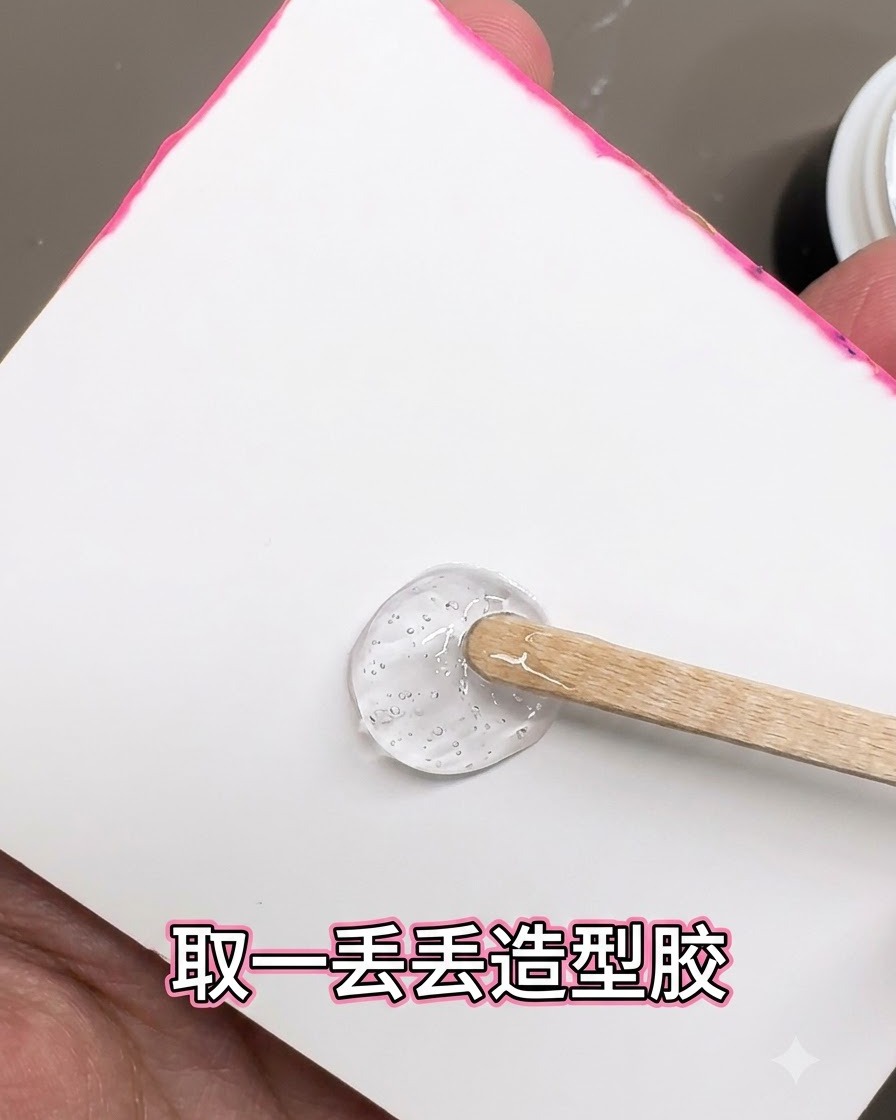 흰색 배경 위에서 나무 스틱으로 투명하고 진한 스타일링 젤 덩어리를 떠내는 모습.