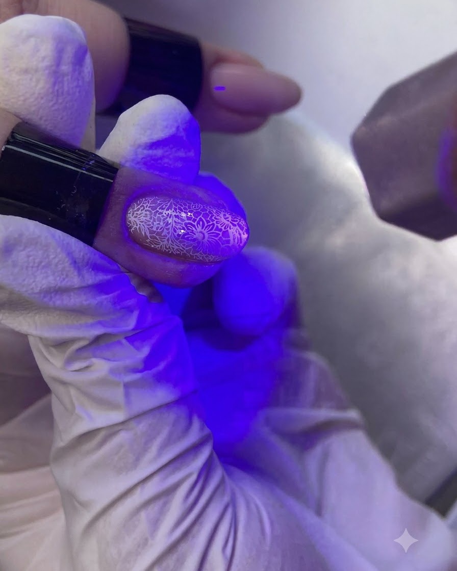장식된 손톱을 경화시키는 퍼플 UV/LED 네일 램프 아래의 손.