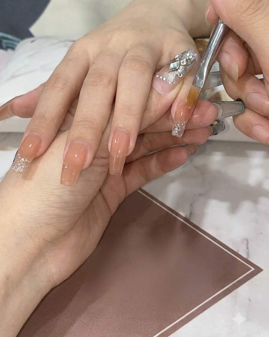깨끗한 플랫 젤 브러시로 누드 네일 위에서 실버 글리터를 아래쪽으로 쓸어내리며 부드러운 그라데이션을 만드는 모습.