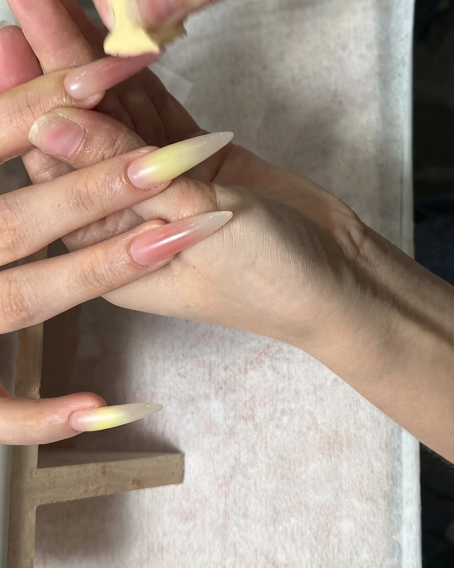 롱 아몬드 네일에 그린과 코랄 레드 톤을 스펀지로 블렌딩하는 시술 장면.